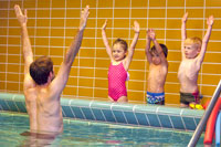 Kinder und Schwimmlehrer bei Trockenübungen
